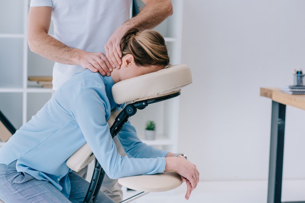 masseur doing seated neck massage for businesswoman